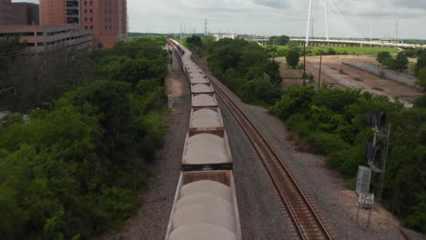 Vista-Aérea-Del-Tren-Largo-Parado-En-La-Vía.-Sobrevolando-Vagones-De-Carga-Con-Carga-Seca-A-Granel.-Drone-Siguiendo-El-Ferrocarril.-Dallas,-Texas,-Nosotros