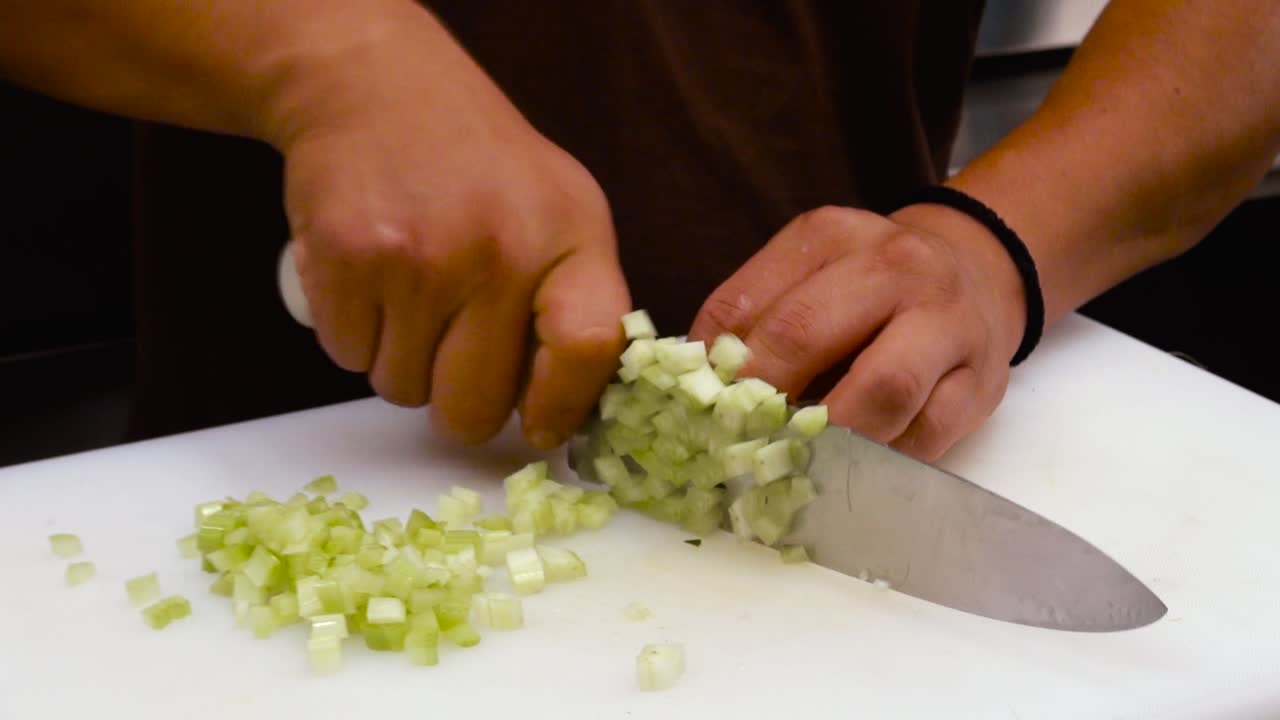close up of a chef's hands slicing fresh vegetables in a restaurant