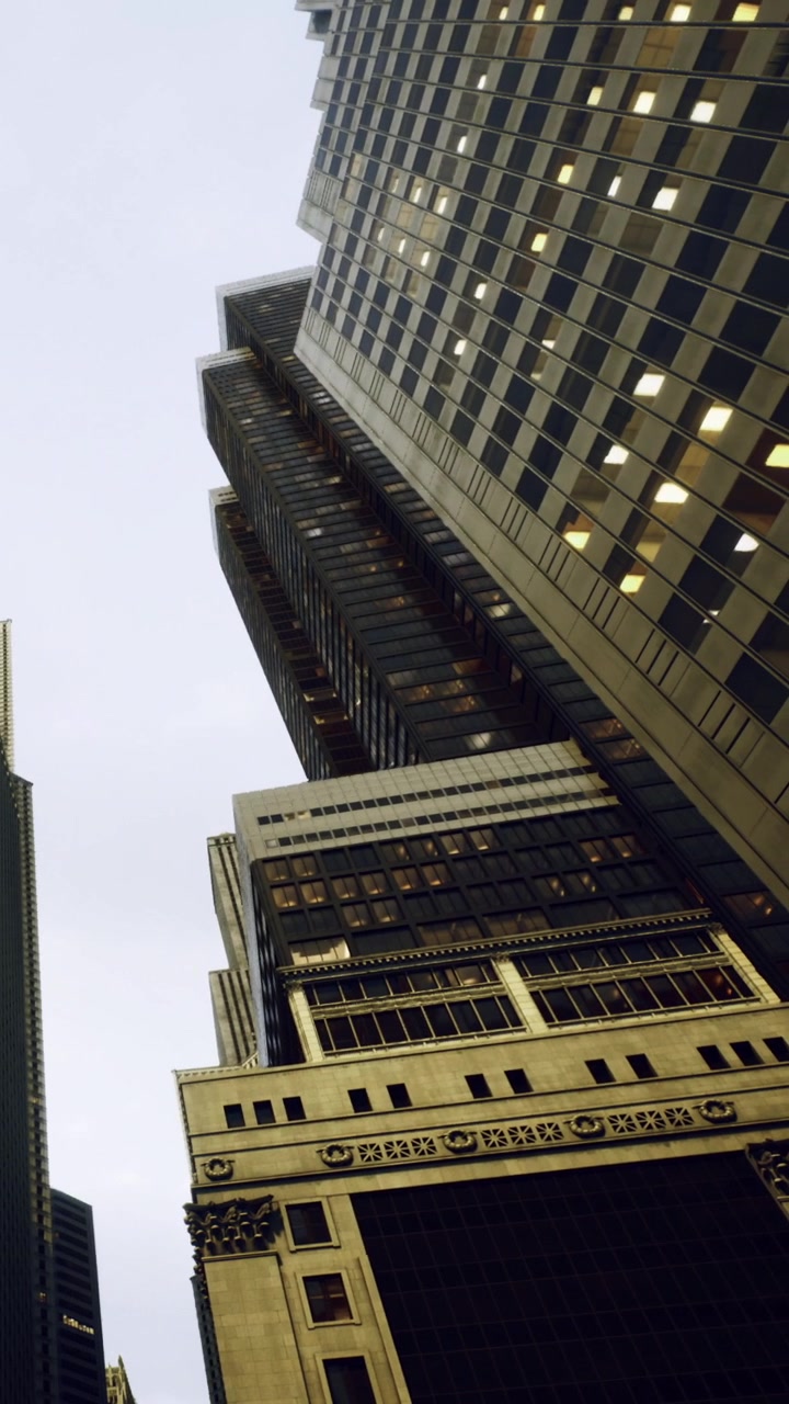 Grattacieli si ergono verso il cielo grigio in un paesaggio urbano con le luci accese