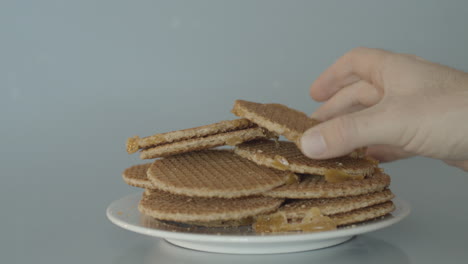 Hand-placing-stroopwafel-on-pile-of-cookies---wide