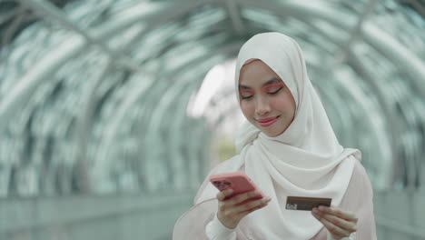 woman using mobile phone and credit card in a city tunnel