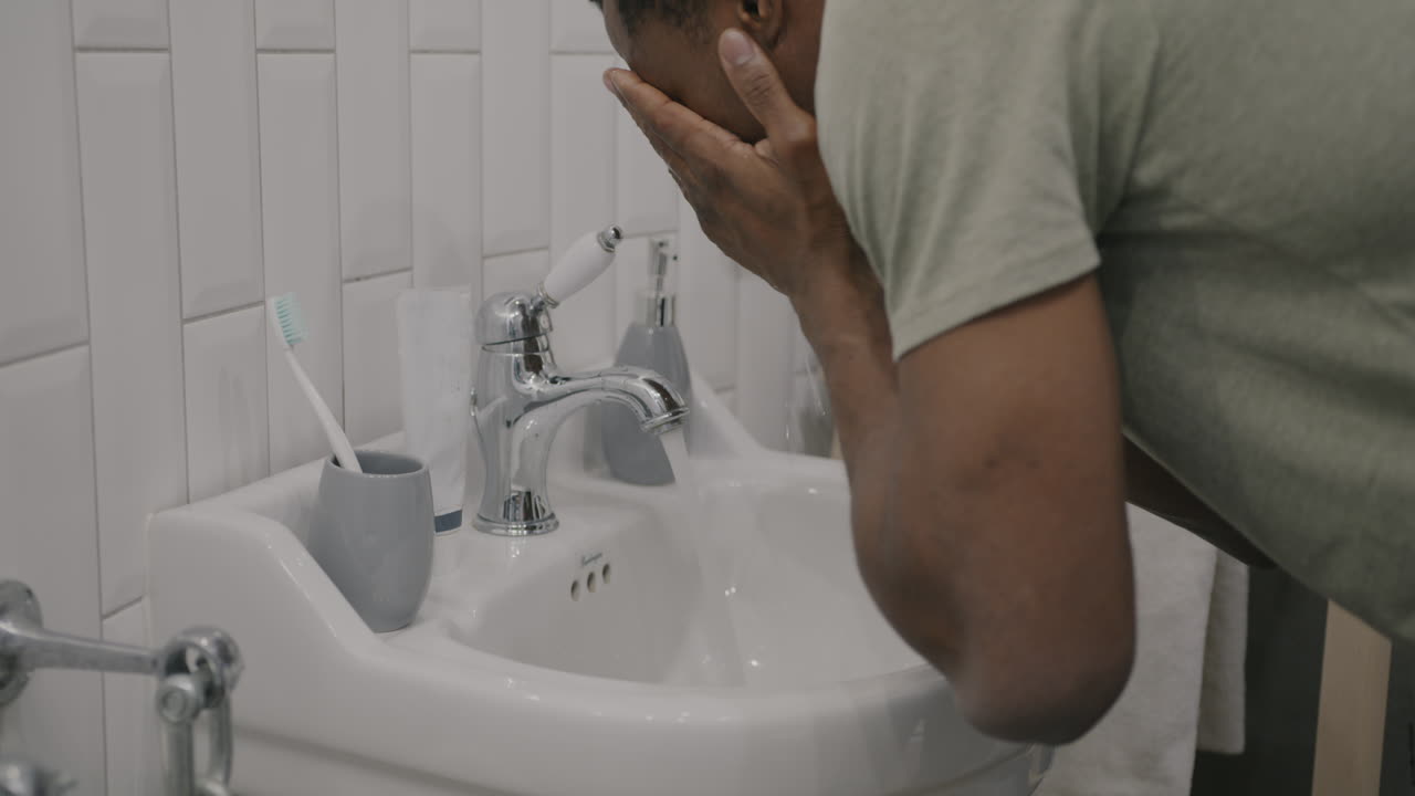 Man washing his face in a bathroom sink