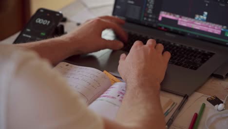 hombre escribiendo en la computadora portátil con temporizador en el teléfono celular en el fondo