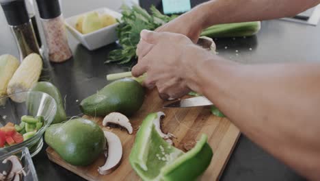 hands of biracial man preparing meal, chopping vegetables in kitchen, slow motion