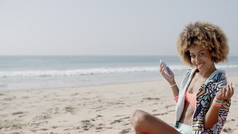 mujer joven con auriculares en la costa del mar