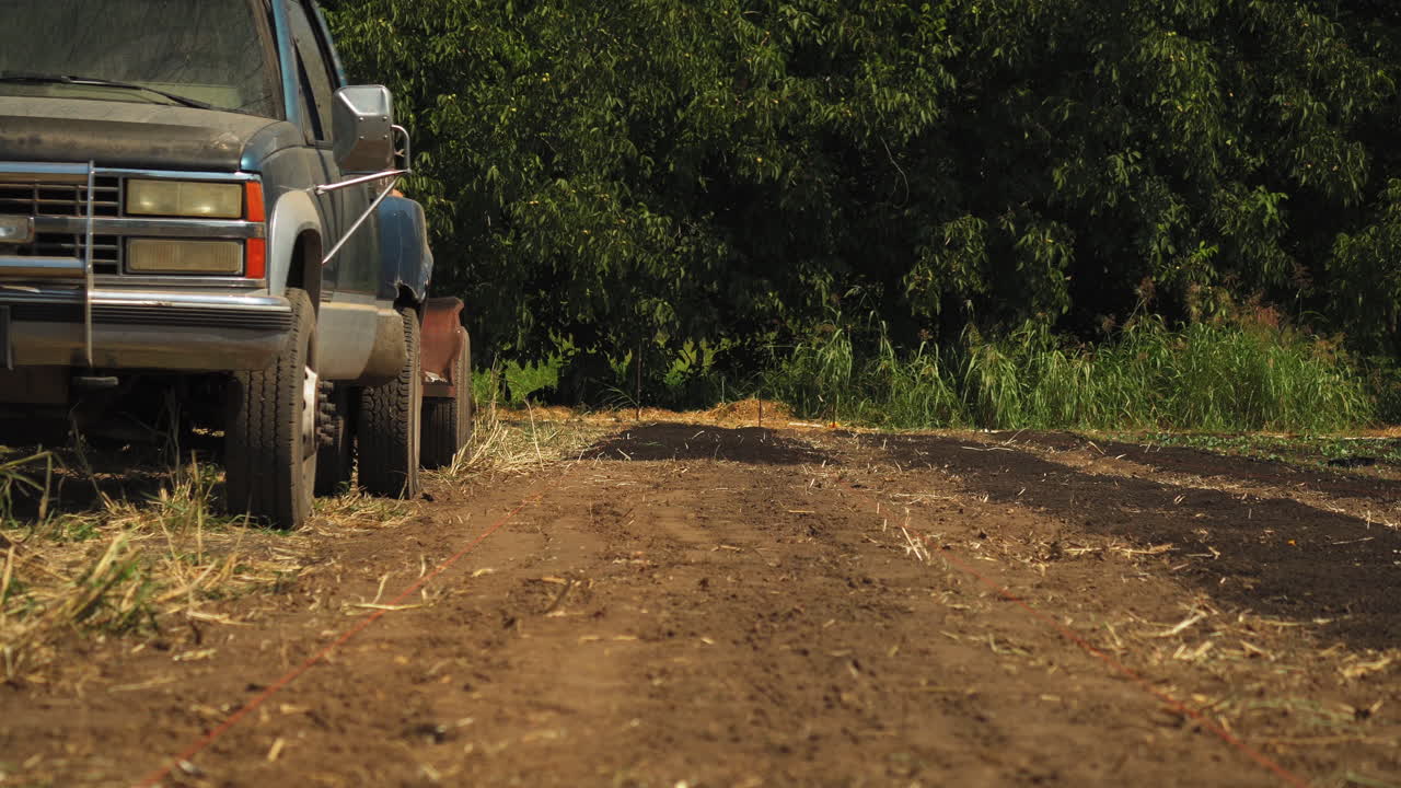chico de campo con sombrero parando el coche en la granja para beber agua de un termo