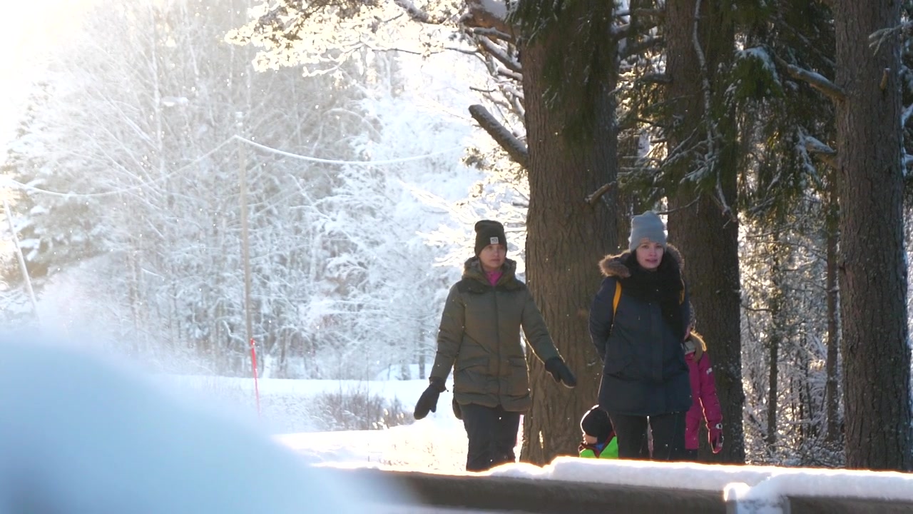 Flergenerasjonsfamilie går i et vinterlandskap og nyter vakker natur, sakte film