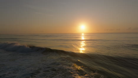 backwards slowmo shot of ocean wave breaking against sunset backdrop in australia