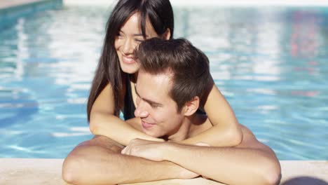 beautiful woman cuddles with her boyfriend in pool