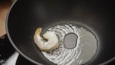 cocinero irreconocible fritando gambas en sartén con aceite caliente
