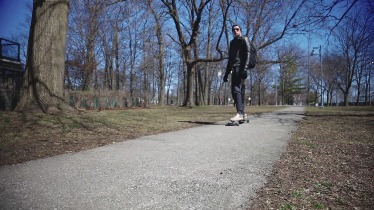 Young Stylish Man Riding A Long Skateboard On Park. - low angle shot
