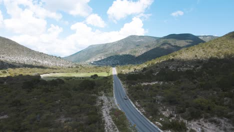 aerial view of jeep driving on road between mountains, adventurous journey through a beautiful landscape, tracking shot