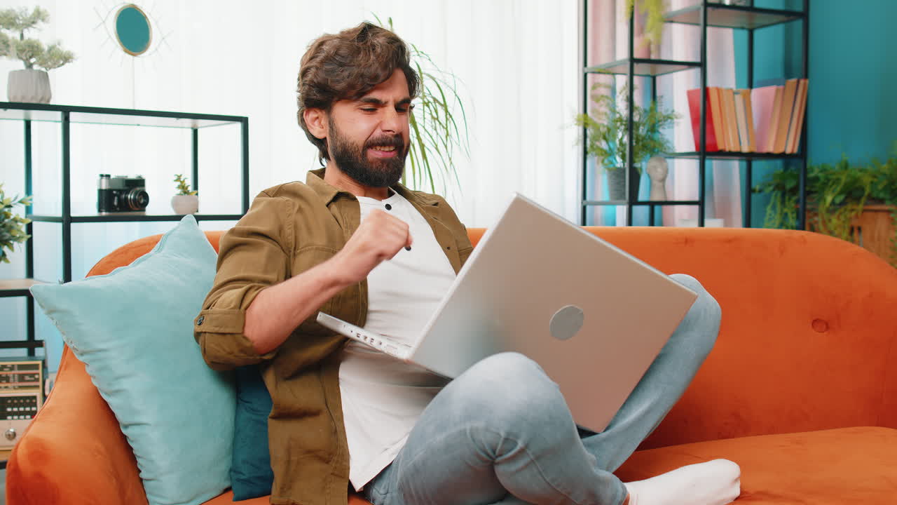 Amazed young man use laptop computer, receive good news message, shocked by victory, celebrate win