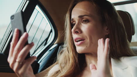 retrato de una mujer de negocios ansiosa hablando en video chat por teléfono en un coche moderno.