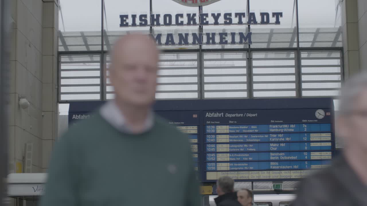 A busy train station in Mannheim with departure boards and people walking around