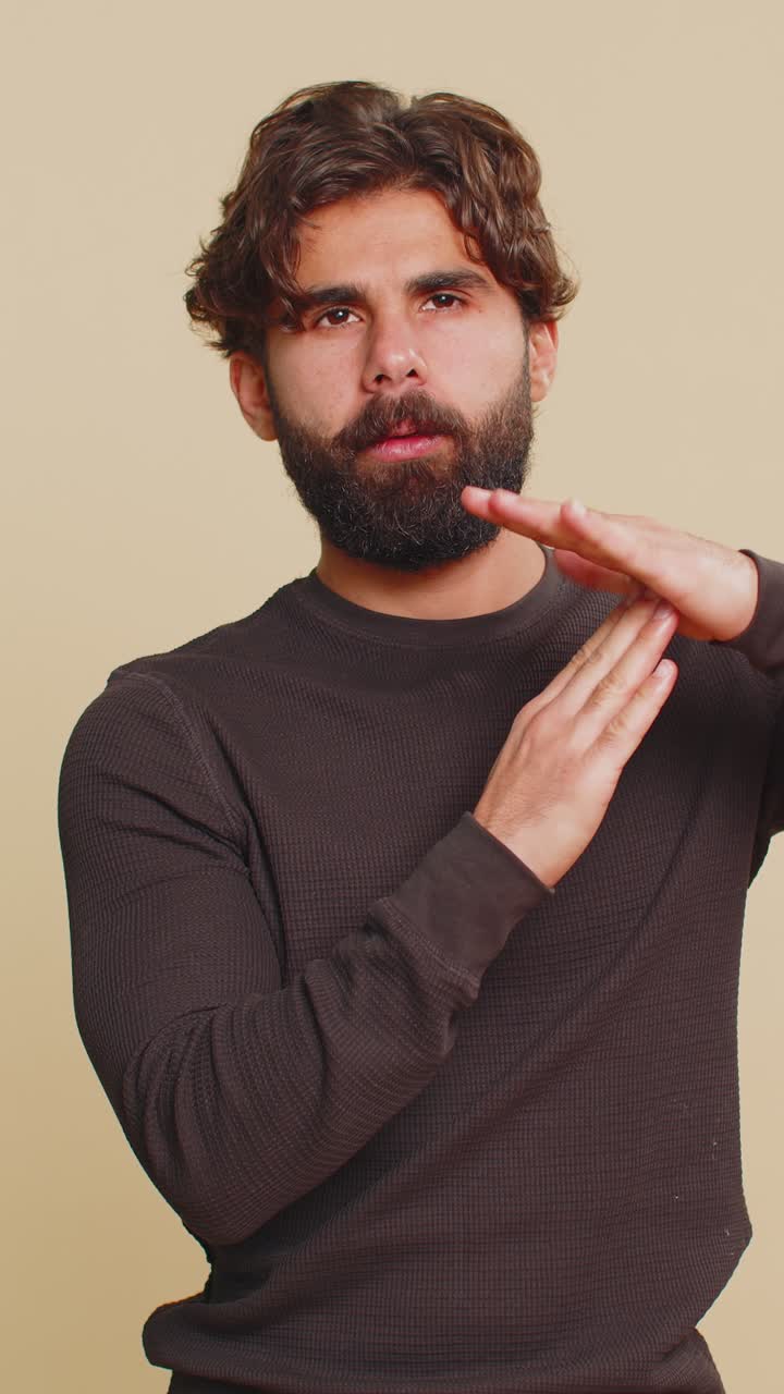 Upset young lebanese man showing timeout gesture limit or stop sign against beige background