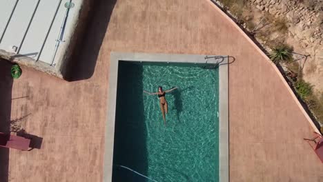 Vista-Aérea-De-Una-Chica-Relajándose-En-Una-Piscina-En-España