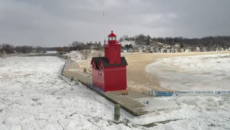 holland, michigan lighthouse in the winter at lake michigan with drone flying towards