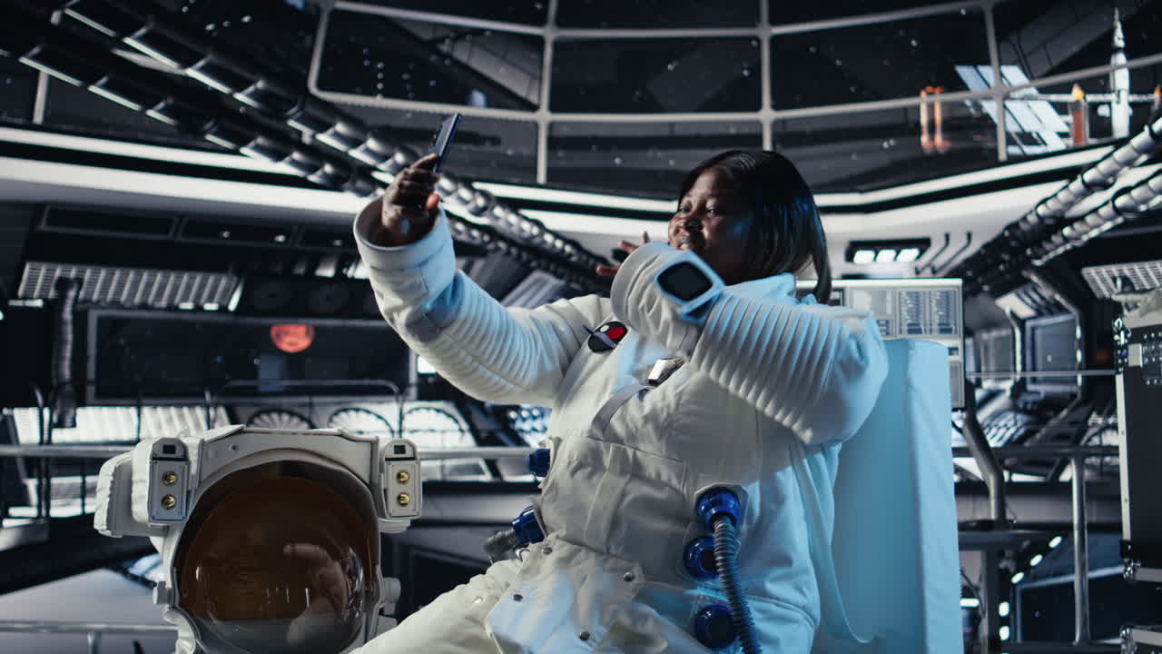 Jolly astronaut having fun in starship doing selfies using smartphone camera