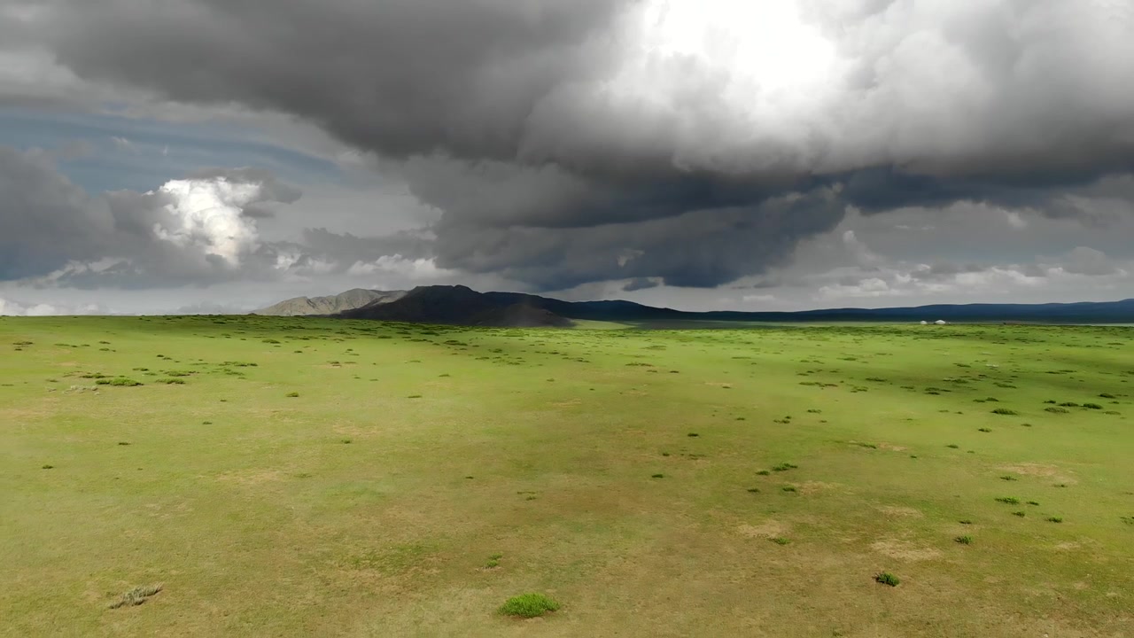 Vista aerea di una vasta prateria verde sotto minacciose nuvole di tempesta