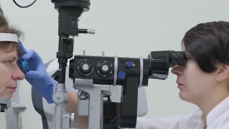 woman doctor is viewing through ophthalmoscope in eyes of patient in ophthalmologic clinic. professional inspection of vision