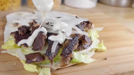 Slow-Motion-Slider-Shot-of-Drizzling-Garlic-Mayo-on-a-Doner-Kebab-in-Naan-Bread-at-Home-in-the-Kitchen