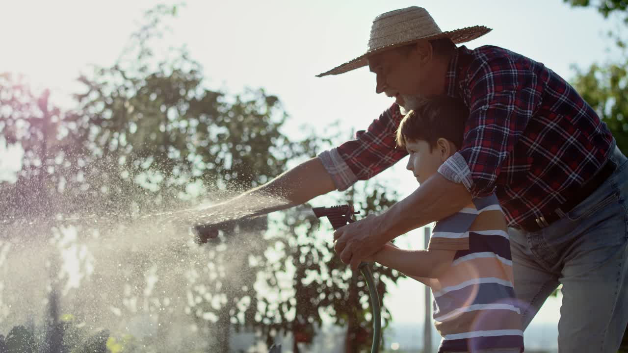 video del nieto regando verduras en el jardín con el abuelo