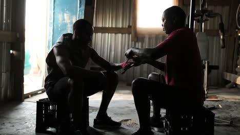 coach tying hand wrap to a boxer in the gym