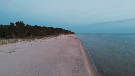 car stuck in sand at the dune sea coast of baltic sea bernati, latvia sun going beyond the horizon illuminating water and clouds in the sky, calm sea waves, romantic mood, wide angle drone shot