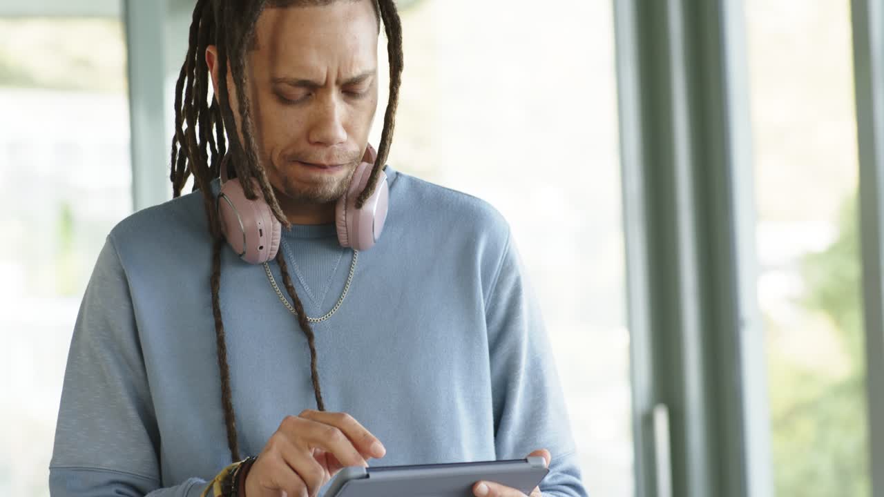 Man tapping and swiping tablet screen in lounge area while reviewing content and pondering