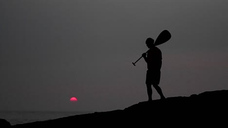 Gebürtiger-Hawaiianer-Spaziert-In-Silhouette-Mit-Einem-Paddel