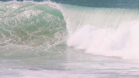 close-up view of powerful ocean waves crashing and forming barrels with white foam and spray.