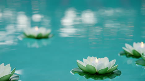 floating battery candles in lotus decorations in swimming pool, 4k slow motion