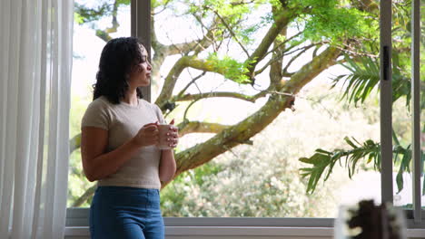 woman enjoying coffee by window, relaxing at home with nature view, copy space