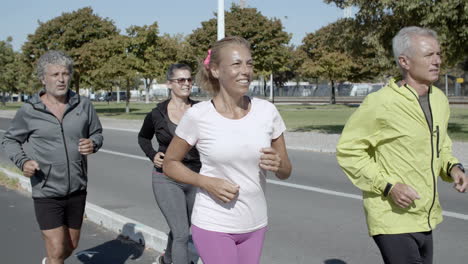 happy active elder joggers running down street