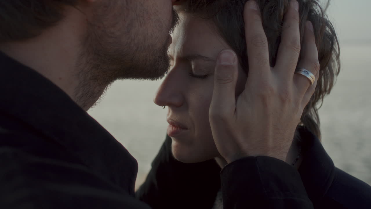 вЂ‹вЂ‹Man Gently Kissing Girlfriend on Forehead in Emotional Moment Outdoors