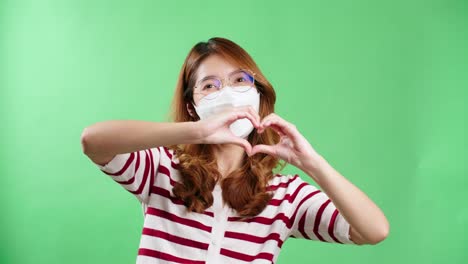 크로마키를 사용하여 스튜디오에서 손으로 하트 기호를 만드는 안경을 쓴 청년