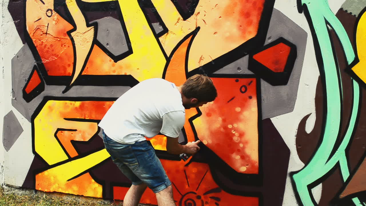 Kunstneren tegner graffiti på et gjerde. Graffiti på et gjerde