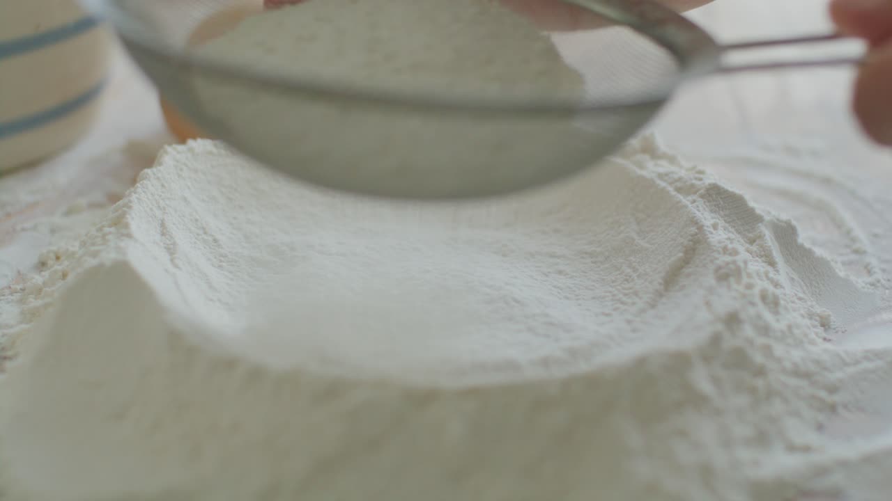 Close-Up of Sifting Flour on Kitchen Table before Dough Preparation