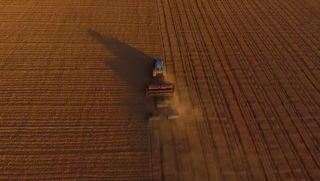 Sowing-fields-with-tractor-and-seeder-in-dusty-field-aerial-view