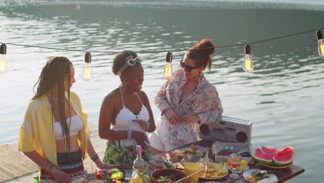 cheerful women talking at lake dinner party