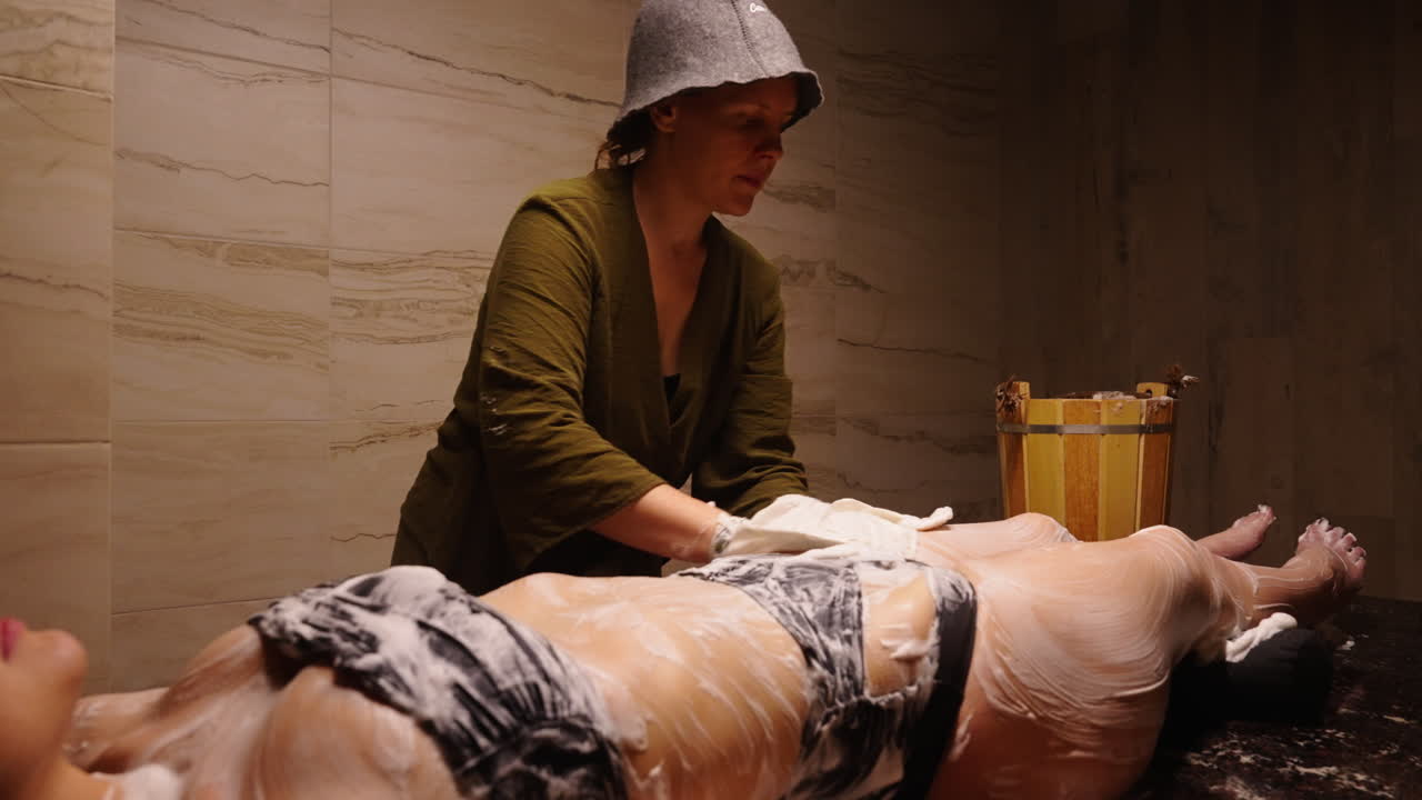 Woman receiving a body scrub treatment at a spa