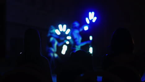 Silhouetten-Von-Zuschauern,-Die-Eine-Tanzshow-Mit-Schöner-Hintergrundbeleuchtung-Sehen