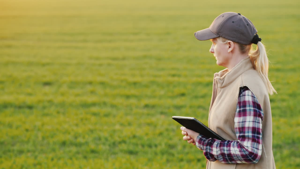 una joven agricultora camina por un campo de trigo con una tableta