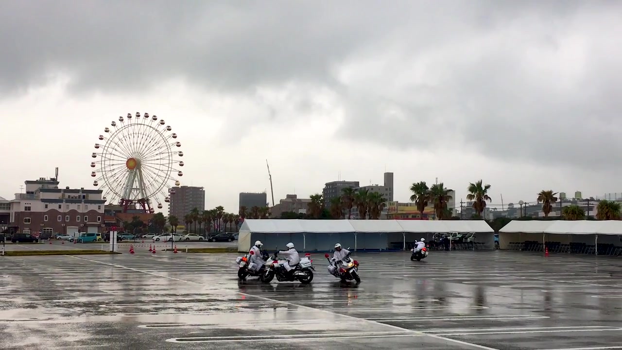 Motociclette che si esibiscono in una formazione coordinata in un parcheggio. Zoom indietro. Sfondo con ruota panoramica.
