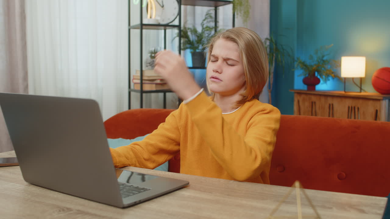 Teenager boy receiving bad news on laptop disappointed with exam results sitting on couch at home