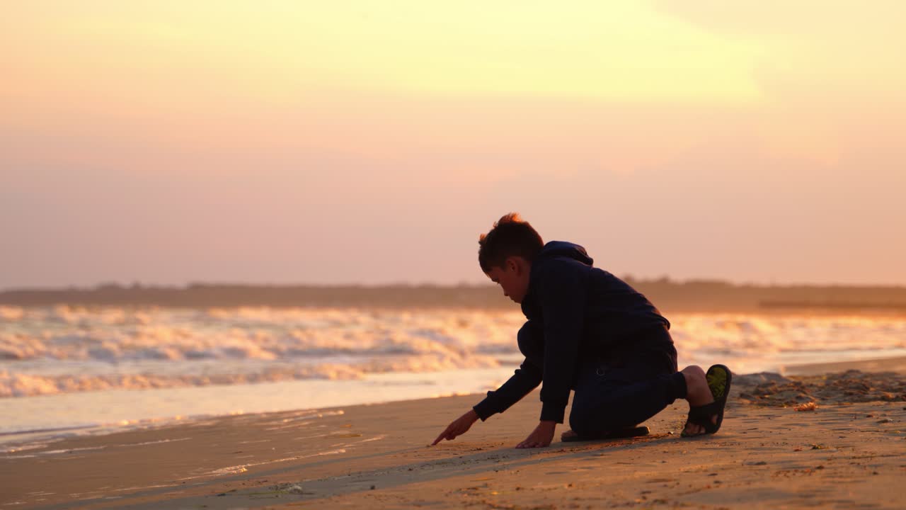 Boy drawing word on sand. Boy at the beach writing the word on the sand