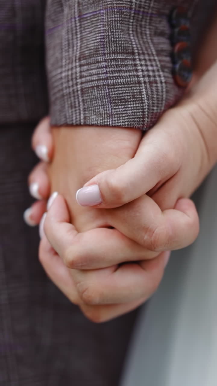 Young newlywed wife holds husband hand braiding fingers in spring park closeup slow motion. New family at wedding ceremony. Celebrating marriage