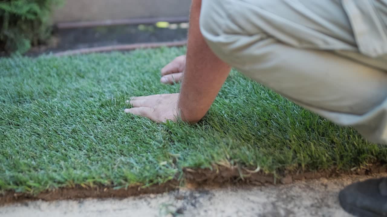정원사 가 목조 울타리 로 사립 마당 에 잔디 를 고 있다