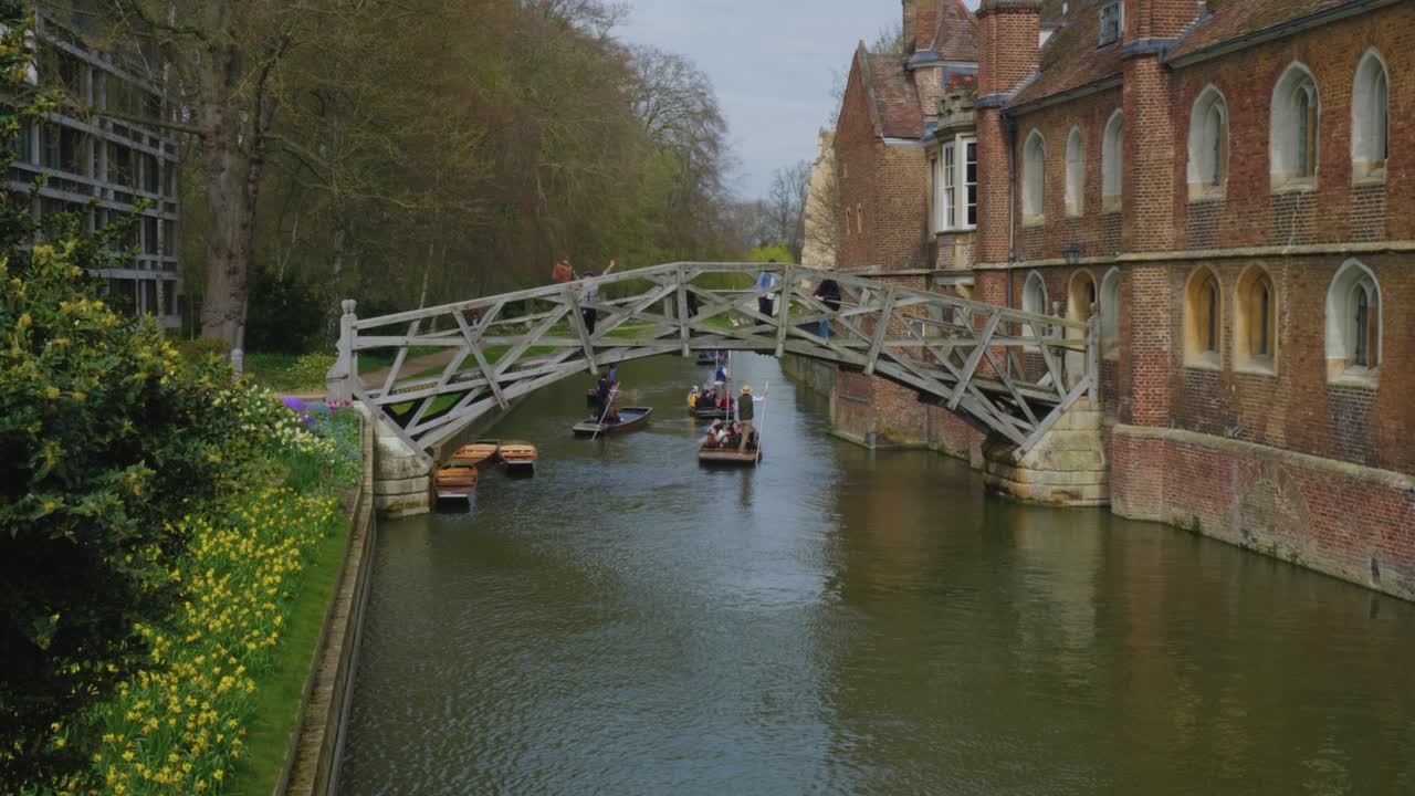 los barcos fluviales son empujados a través de las aguas tranquilas bajo un puente por un guía turístico en inglaterra